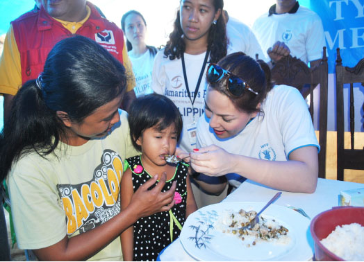 Popular actress KC Concepcion feeds a young girl during her visit in Dulag, Leyte on April 9. Concepcion’s visit was part of her commitment as an ambassador against hunger of the World Food Programme.       												(LITO A.BAGUNAS)