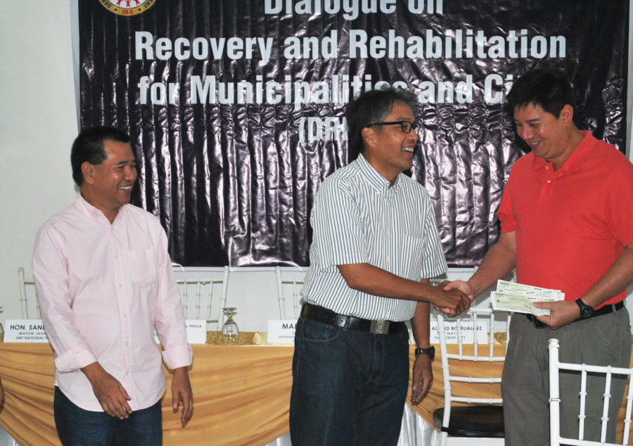 ASSISTANCE. Interior  Secretary Mar Roxas hands over a check  of more than P230 million to Tacloban City Mayor Alfred Romualdez representing  a portion of national assistance for the rehabilitation of public structures destroyed by Yolanda in the city on April 10. Leyte   Governor Leopoldo Dominico Petilla(left) witnesses the turn over of check  in a simple ceremony in Palo town.(LITO A. BAGUNAS) 