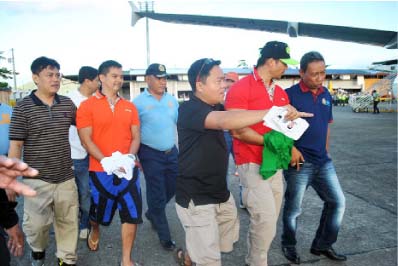 GOTCHA! Fugitive businessman Cedric Lee( in black and blue hiking shorts), who was arrested in a beach resort in Dolores, Eastern Samar last April 26, being escorted by agents of the National Bureau of Investigation back to Manila. Lee and coaccused Zimmer Raz are facing serious illegal detention filed against them by comedian Vhong Navarro.(LITO A. BAGUNAS) (story on page 15)