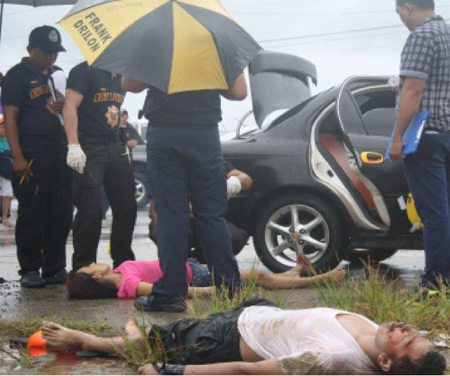 Members of the scene of crime operatives (SOCO) of the Tacloban City Police examines the dead bodies of the victims of an extra-judicial killings that occured at the Daniel Z. Romualdez Airport on Friday early morning. The killings were said to be drug-related. (MEL CASPE)