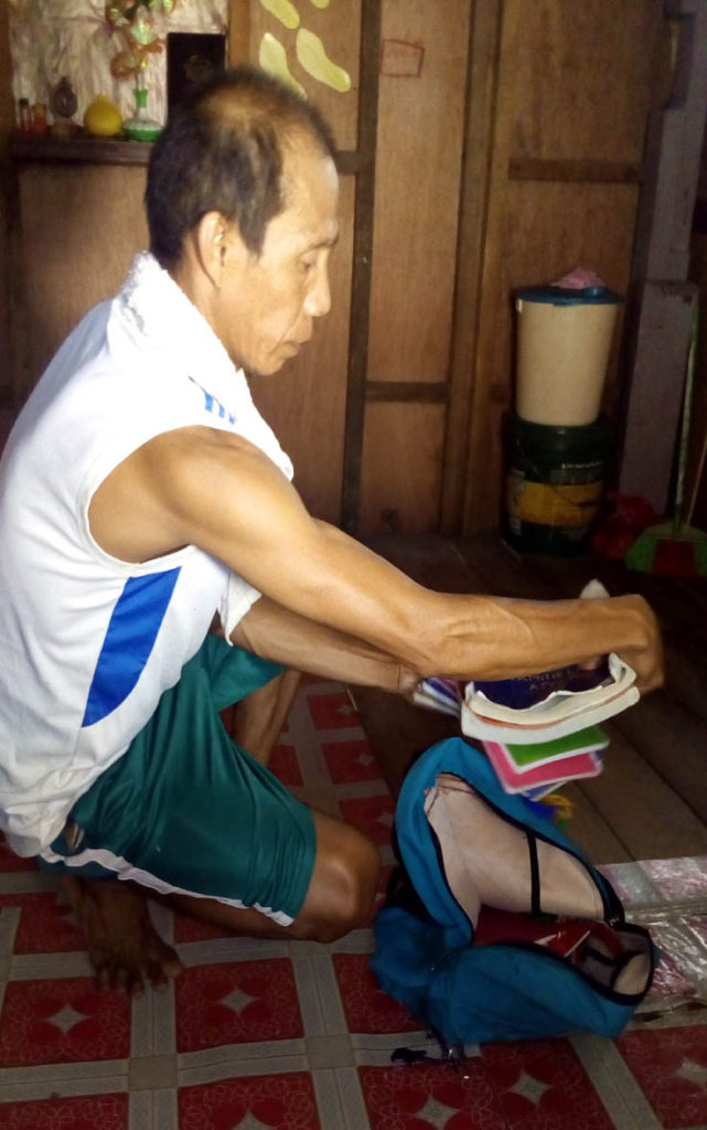 Angelika Bonita’s father, Joel, scans her school belongings inside their house in Barangay 75, Fatima district. The grieving father calls for justice over her grisly murder.  