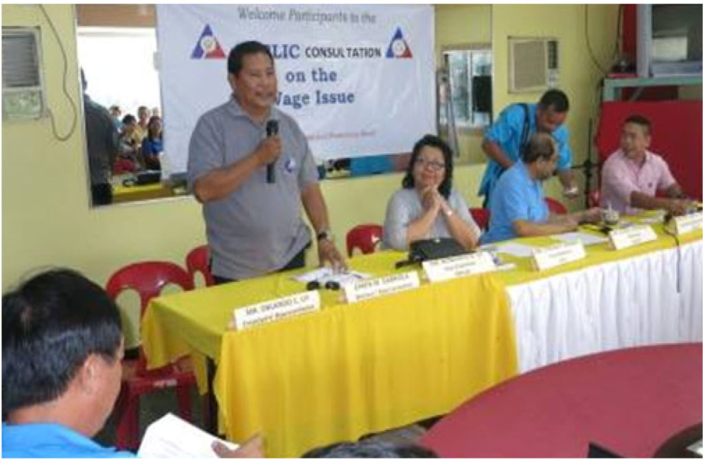 Labor Representative Board MemberEfrenGabriola delivers the opening remarks as the public consultation on wage increase starts.  Next to him is DTI Regional Director Cynthia Nierras (vice chair), DOLE 8 Regional Director Elias Cayanong (chairman), board secretary Reynaldo Soliveres and DOLE 8 ARD Exequiel Ronie Guzman (at the front, partly cropped).  The consultation was held on August 23, 2016 in Catbalogan City.